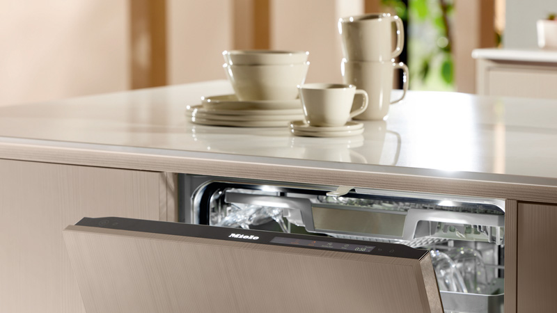 Offener Miele Geschirrspüler in moderner Küche, bereit zum Einräumen – Fokus auf effizientes Spülprogramm QuickPowerWash für sauberes Geschirr in kurzer Zeit