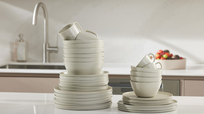 Mehrere gestapelte Teller, Schüsseln und Tassen auf Küchenarbeitsplatte – symbolisiert halbe Beladung eines Miele Geschirrspülers mit flexibler Beladeerkennung